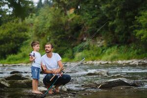 uma pai ensino dele filho quão para peixe em uma rio lado de fora dentro verão brilho do sol foto
