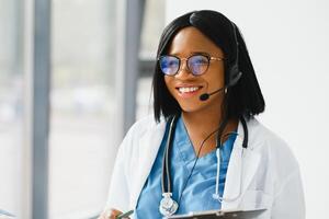 jovem afro-americano médico trabalhando em computador portátil dentro clínica. foto