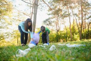 mulher voluntário e pequeno Garoto colheita acima a plástico lixo foto