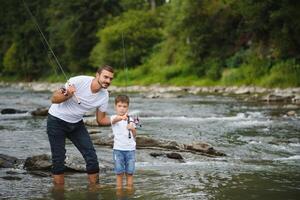 uma pai ensino dele filho quão para peixe em uma rio lado de fora dentro verão brilho do sol foto