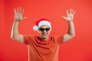 retrato do feliz e animado homem dentro santa chapéu, alegria e ganhando algo, a comemorar Novo ano, em pé sobre vermelho fundo foto