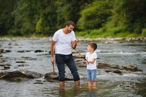 uma pai ensino dele filho quão para peixe em uma rio lado de fora dentro verão brilho do sol foto