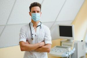 masculino médico dentro mascarar com ultrassom equipamento dentro a clínica escritório foto