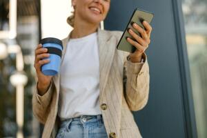 fechar acima do sorridente o negócio mulher é em pé em moderno construção fundo e parece em telefone foto