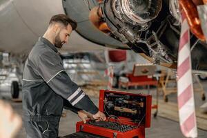 barbudo homem mecânico usando ferramenta caixa dentro aeronave hangar foto