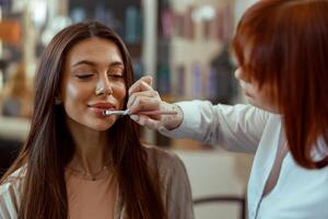 profissional Maquiagem artista aplicando batom com uma escova dentro beleza salão foto