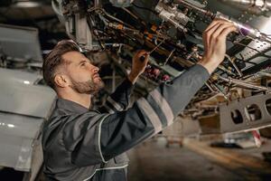 masculino aviação mecânico inspecionando aeronave componentes dentro hangar foto