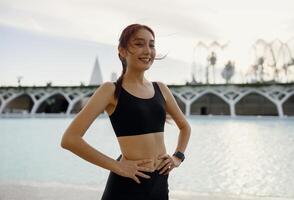 fêmea atleta dentro roupa de esporte ter uma descansar depois de manhã corrida lado de fora e parece Câmera foto