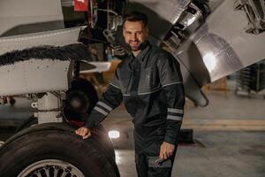 alegre masculino mecânico em pé perto avião dentro hangar foto