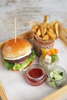 caseiro grelhado plantar Sediada hamburguer com salada, cunhas e tomate molho servido dentro uma servindo borda lado Visão foto