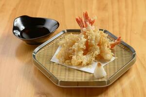 japonês Comida profundo frito ebi tempura camarão dentro uma bandeja com Pimenta molho em de madeira fundo topo Visão foto