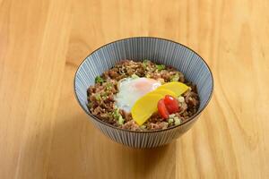 saboroso carne Gyudon com frito arroz, ovo e cebola dentro uma tigela em de madeira fundo topo Visão do japonês Comida foto