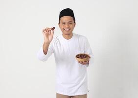 retrato do animado ásia muçulmano homem comendo encontro fruta durante sahur ou quebra a rápido. cultura e tradição em Ramadã mês. isolado imagem em branco fundo foto