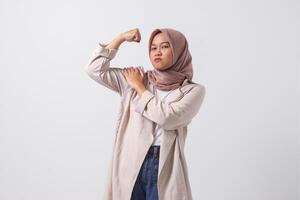 retrato do animado ásia hijab mulher dentro casual terno mostrando Forte bíceps, demonstrando força. empresária conceito. isolado imagem em branco fundo foto