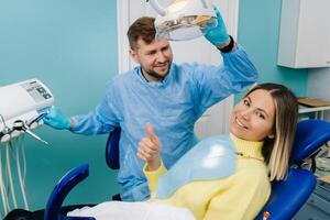 lindo menina paciente mostra a classe com dela mão enquanto sentado dentro a Dentistas cadeira foto