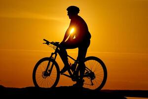 silhueta do uma bicicleta em céu fundo em pôr do sol em uma montanha topo. foto