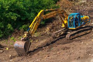 amarelo retroescavadeira com hidráulico pistão braço. pesado máquina para escavação dentro construção local. foto