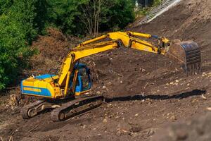 retroescavadeira amarela com braço de pistão hidráulico contra céu azul claro. máquina pesada para escavação no canteiro de obras. máquinas hidráulicas. enorme escavadora. indústria de máquinas pesadas. Engenharia Mecânica. foto