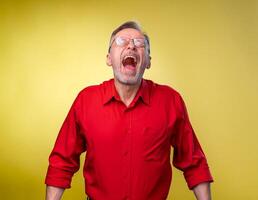 Senior homem é em pé com aberto boca e fechadas boca. isolado contra amarelo fundo. feliz emoções. foto