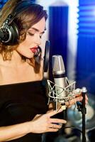 lindo jovem cantor quem gravado uma música dentro uma profissional gravação estúdio. fêmea vocalista foto