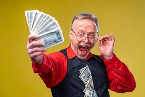feliz saiu homem dentro óculos e vermelho camisa segurando grupo do dinheiro, olhando às Câmera, isolado sobre amarelo fundo foto