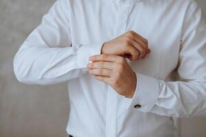 a homem colocar em dele camisa e endireita abotoaduras. a noivo apertar abotoaduras em a algemas do a camisa. a homem de negocios apertar abotoaduras em a algemas do a camisa. conceito bem sucedido homem de negocios. foto