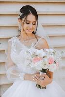 retrato. uma morena noiva dentro uma vestir e uma véu, com uma diadema, poses com uma ramalhete. prata joia. lindo Maquiagem e cabelo. outono casamento. celebração foto