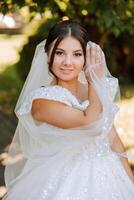Casamento retrato. uma morena noiva posando dentro natureza, coberto com uma grandes véu. lindo inventar. renda vestir. Casamento cerimônia foto