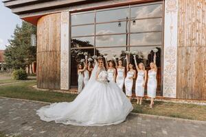 a noiva dentro uma grandes Casamento vestir com uma véu poses dentro frente do dela amigos dentro branco vestidos foto