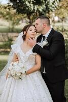 uma jovem noiva e noivo ternamente abraço dentro a raios do a outono Sol. concurso e lindo jovem menina noiva. uma homem Beijos dele amado. contra a fundo do uma lindo jardim foto