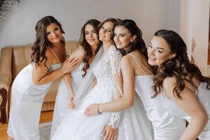 retrato do a noiva com dela amigos. elegante e à moda noiva com dela amigos dentro Coincidindo vestidos dentro a quarto dentro a manhã. muitos lindo meninas dentro 1 foto. foto