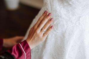manhã retrato do uma luxuoso e lindo noiva dentro uma hotel dentro uma luxuoso quarto dentro vermelho pijamas em pé Próximo para dela Casamento vestir. foto