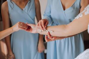 manhã do a noiva. uma dama de honra ajuda a noiva apertar a botões em dela mangas. amigas Socorro a noiva apertar dela vestir foto