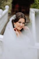 Casamento retrato. uma morena noiva é posando dentro natureza, coberto com uma grandes véu. lindo mãos. renda vestir. foto