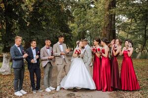Casamento foto sessão dentro natureza. a noiva e noivo beijo e seus amigos