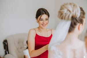 damas de honra alegrar dentro a manhã, ajudando para apertar a botões em a Casamento vestir e preparar para a Casamento cerimônia. elas levar fotos, sorriso, Socorro a noiva com dela sapato. foto