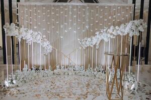 a foto zona às uma Casamento ou aniversário celebração é decorado com flores e iluminado de artificial luz