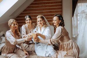foto com damas de honra bebendo champanhe a partir de óculos dentro a manhã dentro uma lindo hotel. foto do uma lindo jovem noiva e dela amigos dentro Coincidindo vestidos bebendo champanhe antes a casamento.