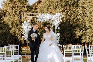 uma Casamento casal é caminhando dentro natureza em a outono dia. feliz jovem noiva e elegante noivo segurando mãos. uma à moda casal do recém-casados em seus Casamento dia. foto