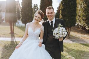 uma Casamento casal é caminhando dentro natureza em a outono dia. feliz jovem noiva e elegante noivo segurando mãos. uma à moda casal do recém-casados em seus Casamento dia. foto