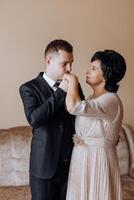 mãe ajuda dela adulto filho preparar para a Casamento cerimônia. a emocional e tocante momento às uma casamento. uma mãe abraços dela filho foto