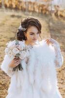 retrato. uma morena noiva dentro uma vestir e uma véu, com uma diadema, poses com uma ramalhete. prata joia. lindo Maquiagem e cabelo. outono casamento. celebração foto