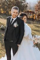 Casamento casal em uma andar dentro a outono parque. a noiva dentro uma lindo branco vestir. amor e relação conceito. noivo e noiva dentro natureza ao ar livre foto