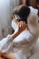 fechar-se morena noiva com moda Casamento Penteado e inventar. uma jovem noiva com uma sofisticado nupcial penteado dentro de casa de uma janela foto