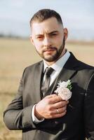 retrato do uma bonito jovem noivo em a outono dia ao ar livre dentro a elegante terno. ao ar livre foto. bonito homem dentro uma o negócio terno. foto