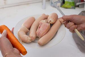 mãos segurando uma prato do Comida com fervido salsichas. foto