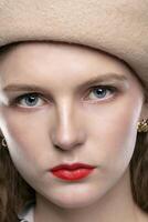 fechar acima retrato do uma jovem lindo mulher dentro uma bege boina e vermelho lábios. foto
