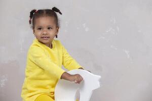 pequeno africano americano menina dentro amarelo roupas mostra língua. engraçado criança. foto