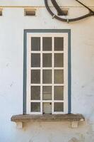 uma branco estilo grego de madeira janela este estava anteriormente usava Como uma contador dentro a velho construção este é agora não mais tempo usava foto