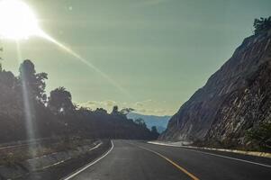 enrolamento rodovia dentro a montanhas com falésias ao lado às crepúsculo foto